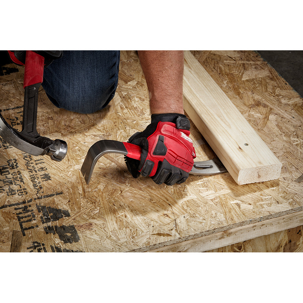 Red and black Milwaukee pry bar with curved end being used to lift lumber on OSB surface.
