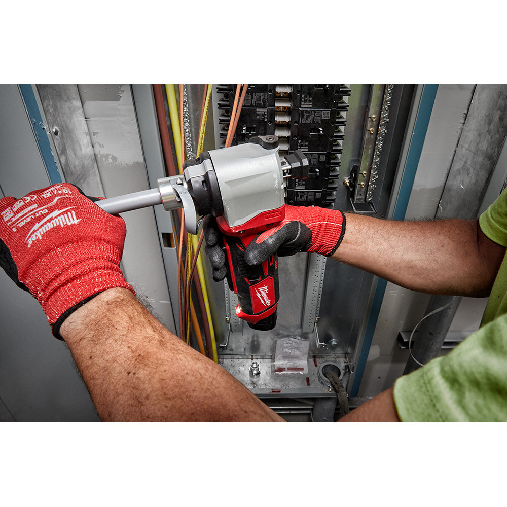 Handheld cordless cable stripper with white and red housing being used on electrical wiring inside a panel by a worker wearin