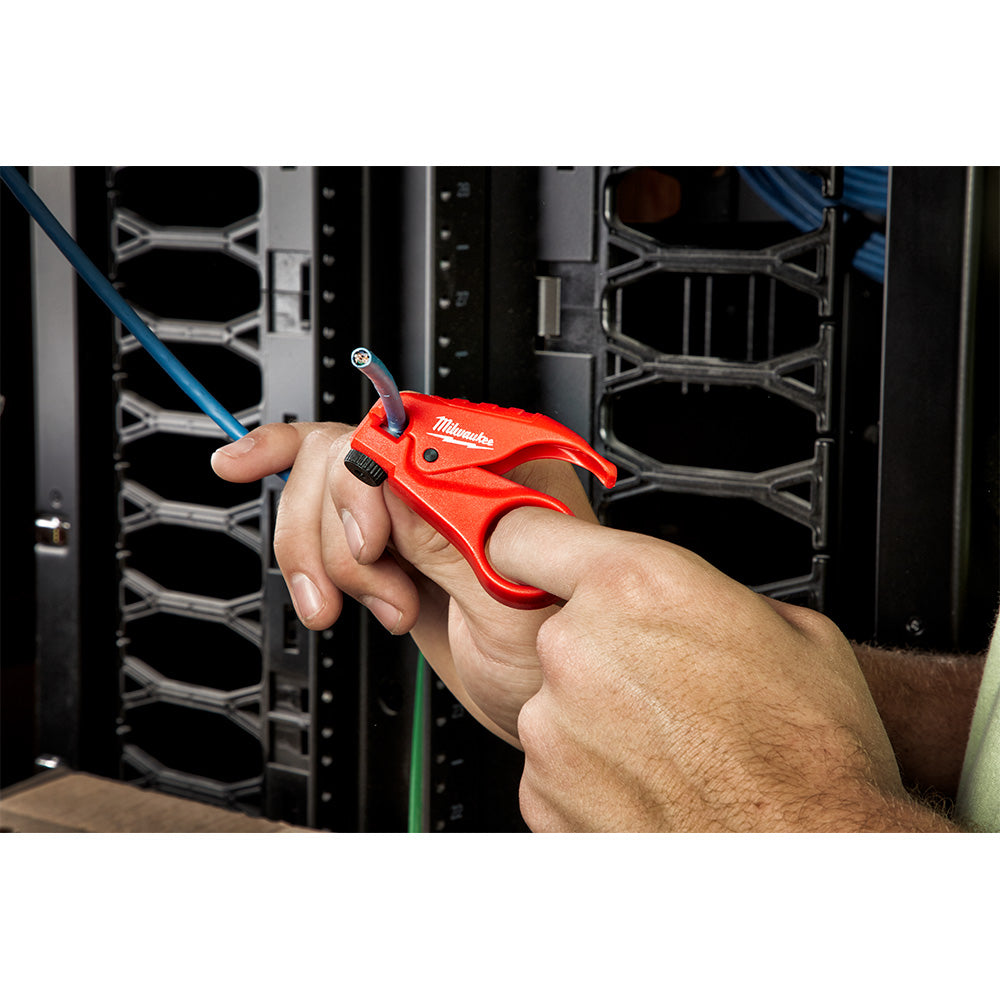 Red Milwaukee wire stripper tool held in hand, stripping blue twisted pair cable in server rack environment.
