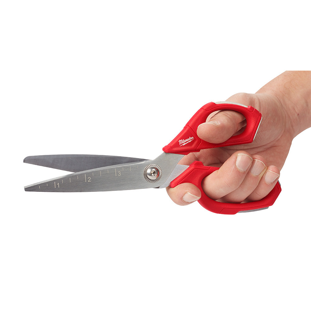 Milwaukee jobsite scissors with red handles and stainless steel blades held in hand.