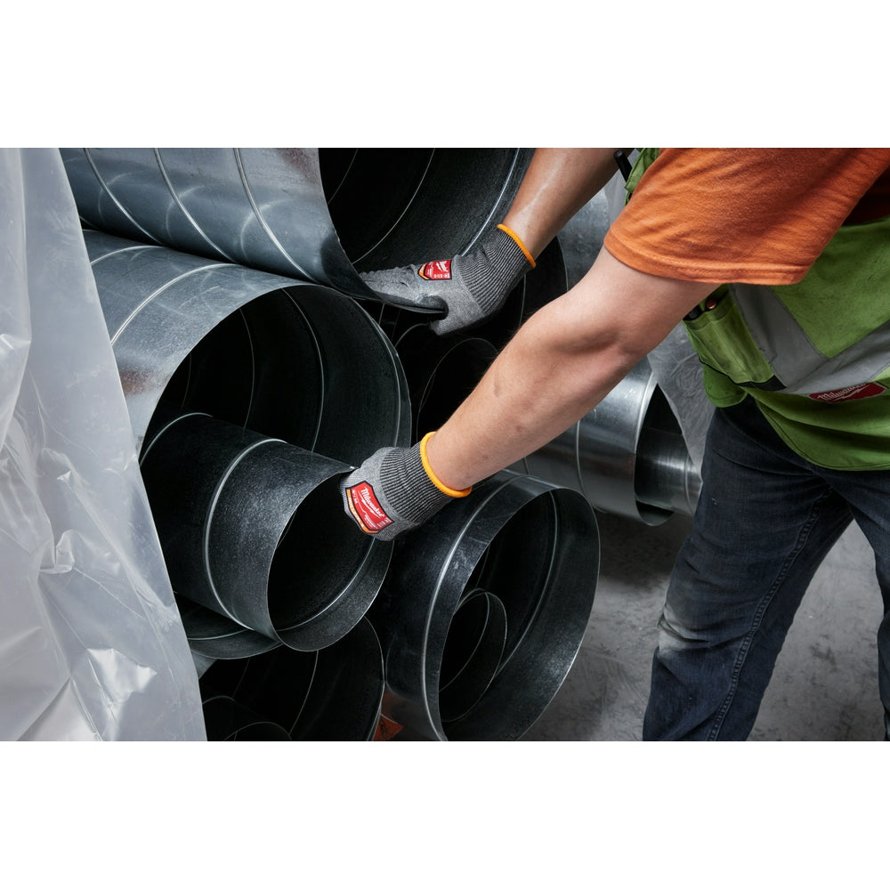 Gray and black nitrile dipped gloves with yellow stripe worn while handling metal pipes.