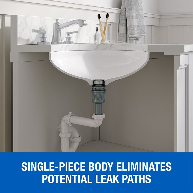 Polished chrome pop-down sink drain installed under white ceramic bathroom sink with white PVC piping visible below.