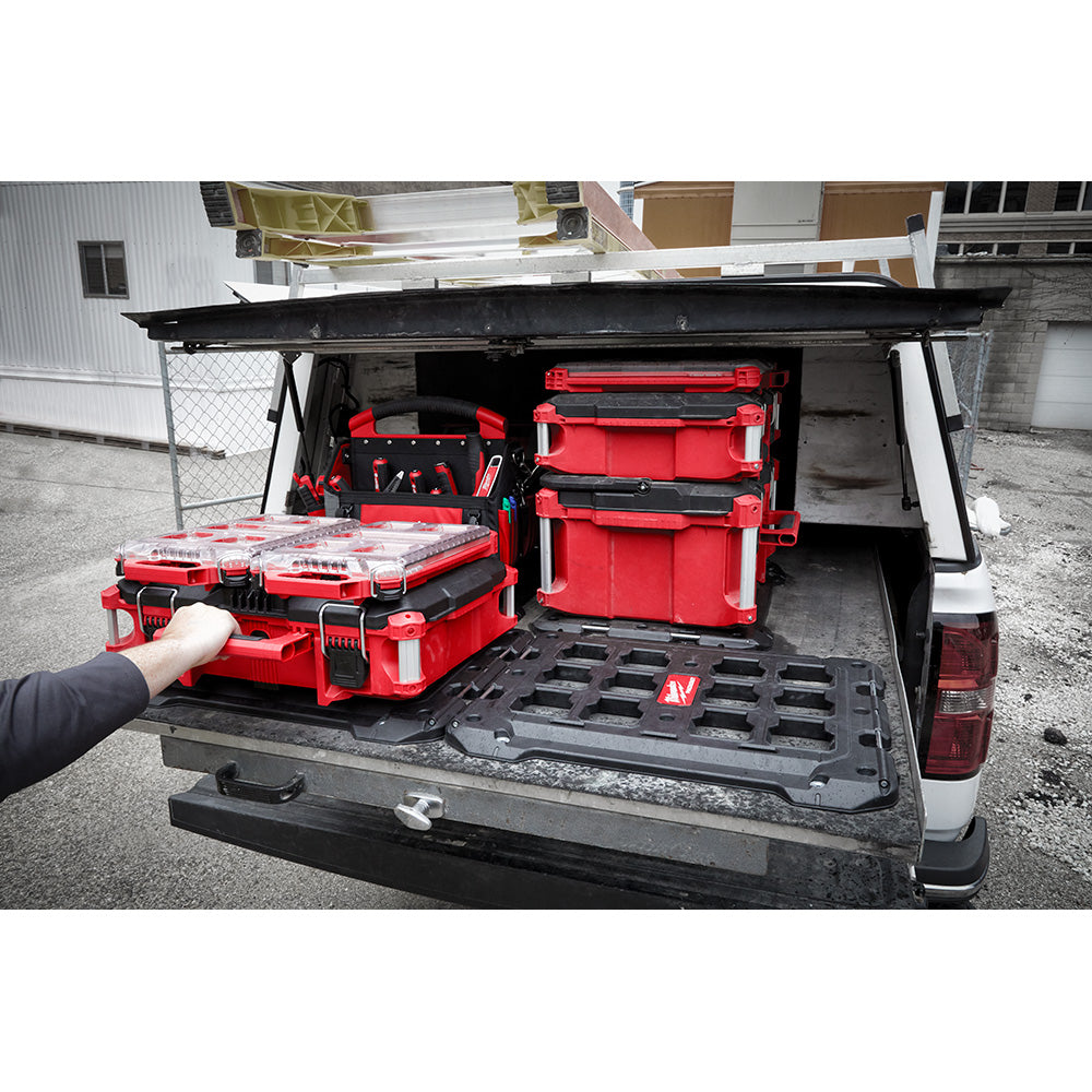 Black plastic mounting plate with grid pattern installed in truck bed with red PACKOUT storage boxes.