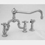 Satin nickel bridge kitchen faucet with curved spout, handles, and separate side spray attachment.