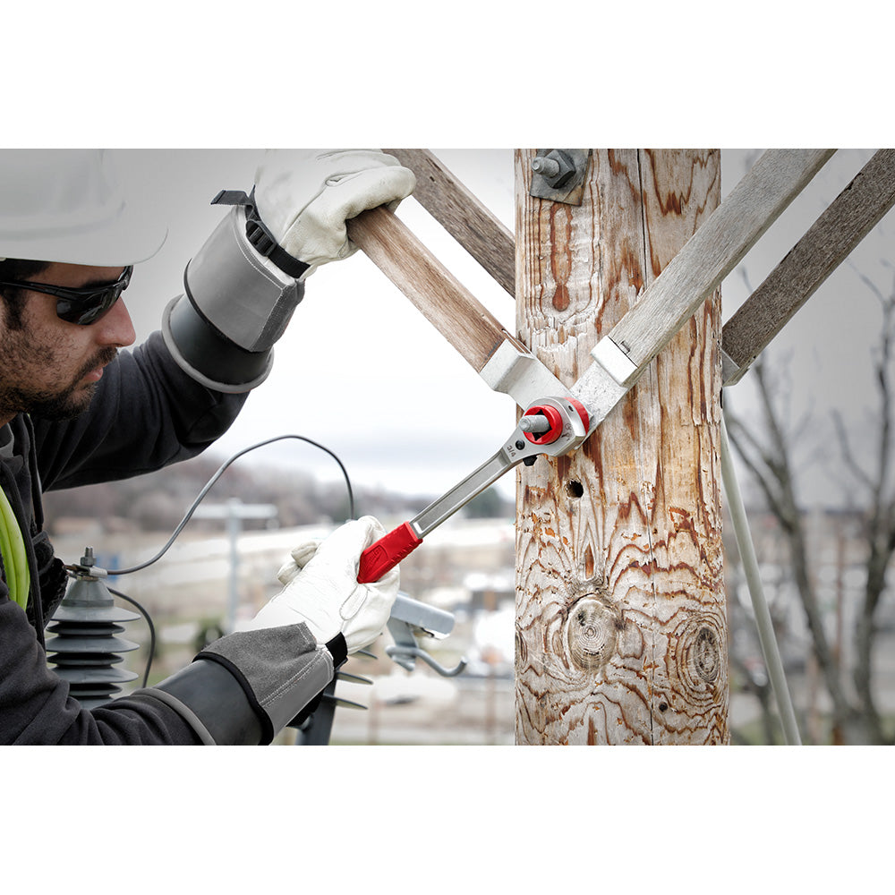 Lineman's ratcheting wrench with red accents being used on utility pole hardware by worker in safety gear.