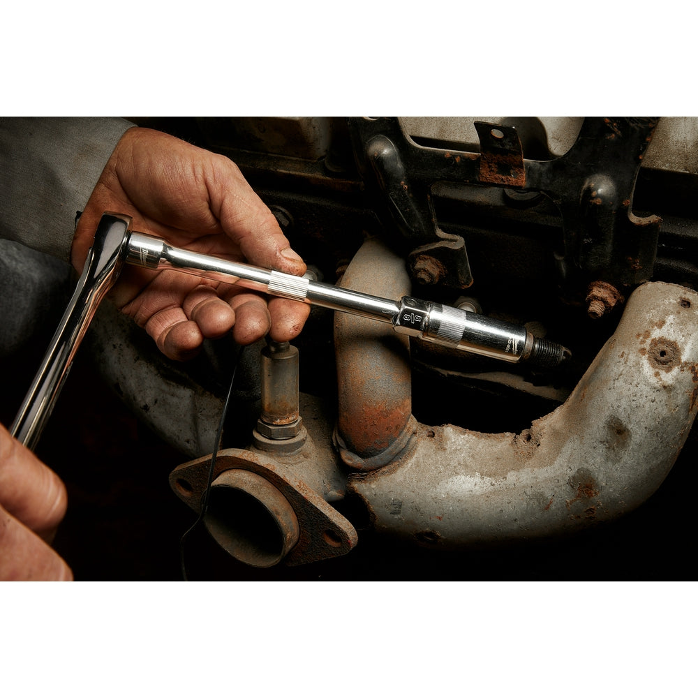 Chrome spark plug socket with 3/8" drive held in hand over engine spark plugs.