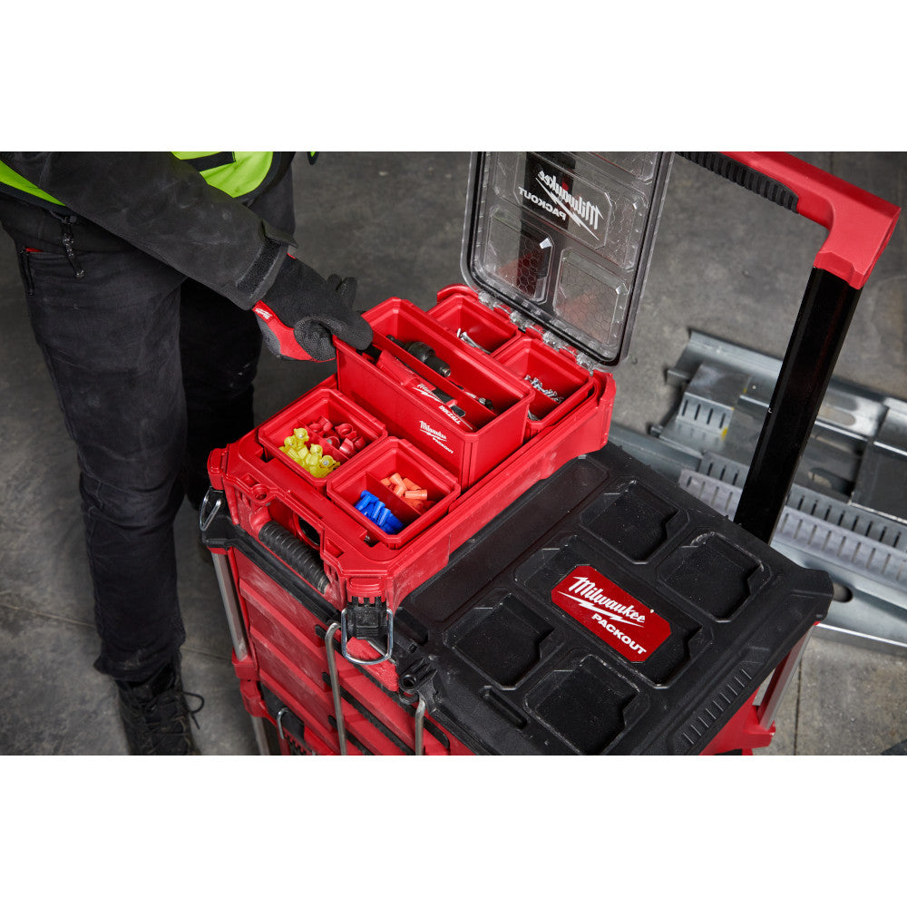 Two Milwaukee red and black PACKOUT storage bins stacked, with top bin containing removable dividers holding various small pa