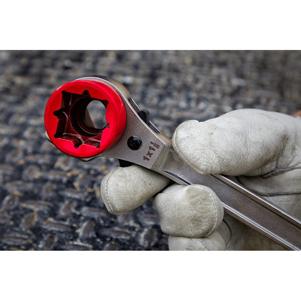 Milwaukee ratcheting wrench with red grip head and milled strike face, held in gloved hand.