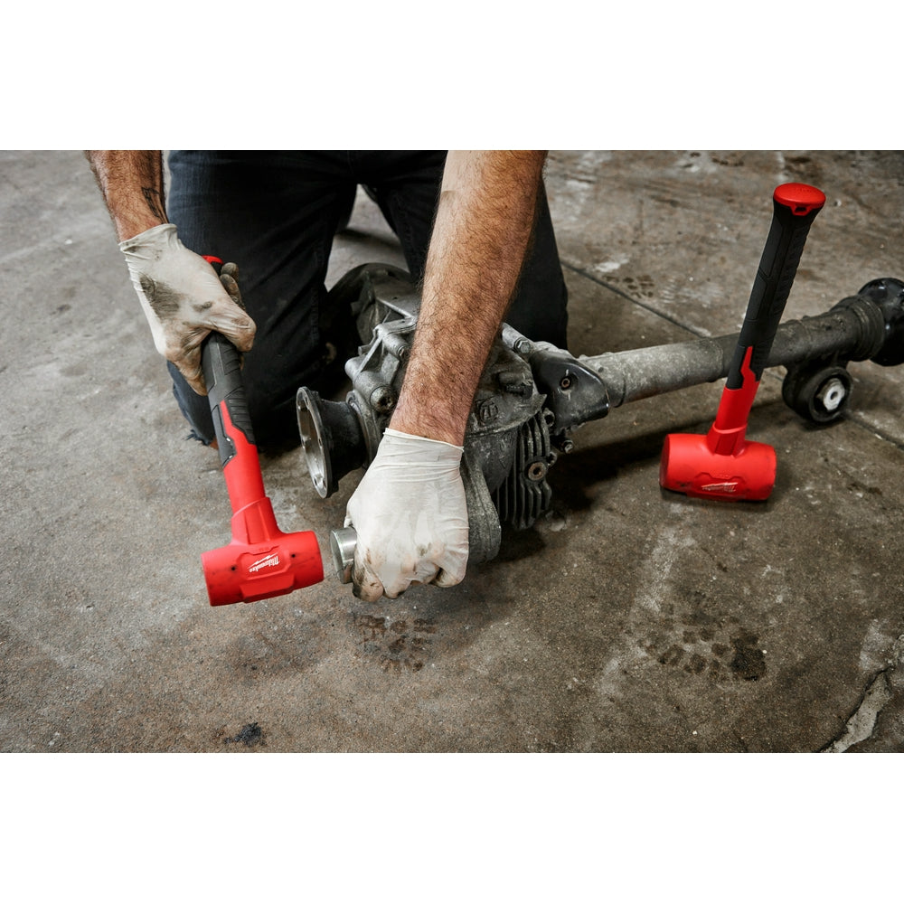 Dead blow hammer with red head and black handle being used on concrete surface by person wearing work gloves.