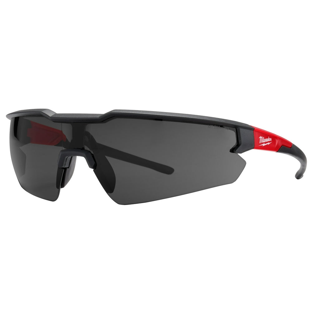 Milwaukee safety glasses with dark tinted lenses, black frames, and red accents on the arms.
