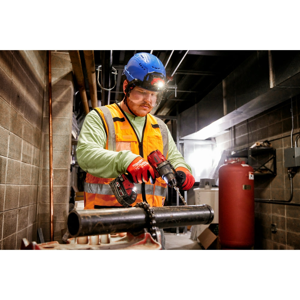 Worker wearing blue hard hat with attached clear visor lens while operating power tool in industrial setting.