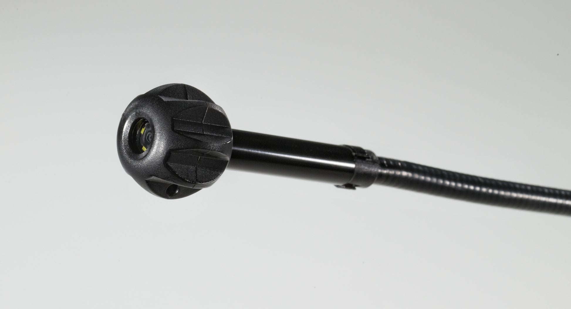 Black pipe guide attachment with ribbed grip handle and yellow-accented connector head on flexible shaft.
