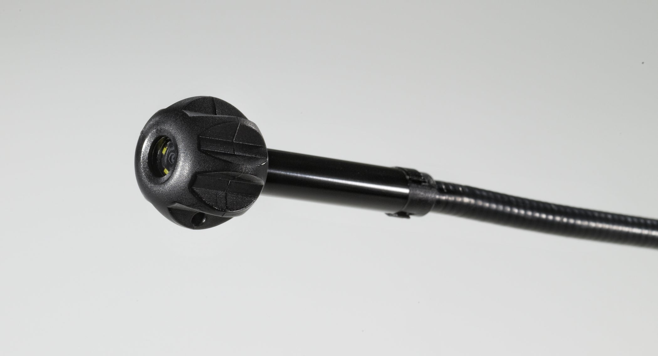 Black pipe guide attachment with ribbed grip handle and yellow-accented connector head on flexible shaft.