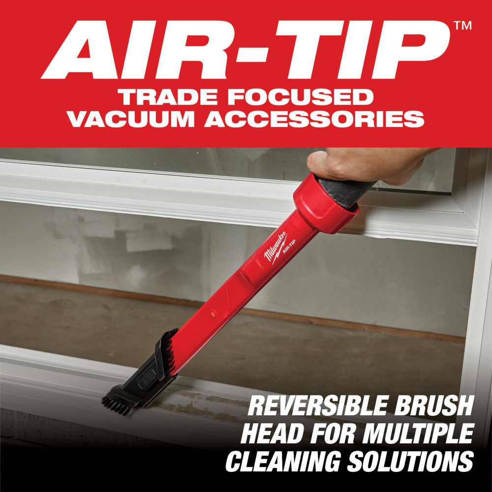 Red vacuum attachment tool with reversible brush head being used to clean a window frame.
