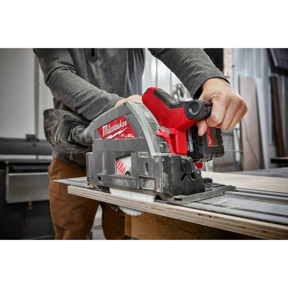 Milwaukee M18 FUEL track saw with red and black housing being used to cut wood on a guide rail.