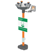 Pedestal-mounted eyewash station with stainless steel bowl, four orange spray nozzles, orange pole, green signage, and contro