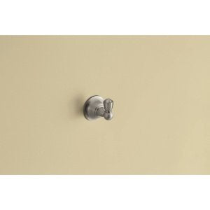 Brushed nickel wall-mount robe hook with cylindrical knob on beige wall.