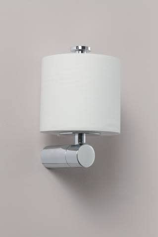 Chrome paper holder with cylindrical base and white paper roll mounted on beige wall.