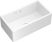 White fireclay farmhouse apron front kitchen sink with single bowl and drain.