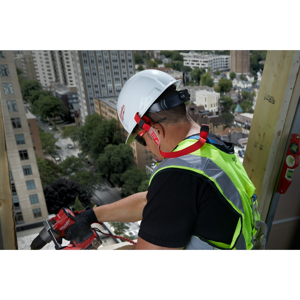Red hard hat lanyard with reflective stripe attached to white safety helmet worn by construction worker on high-rise building