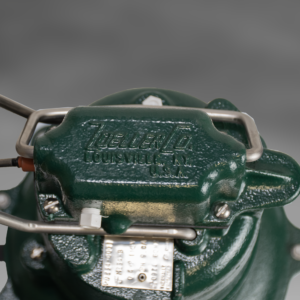 Green cast iron sewage pump with white handles and attached electrical cord.