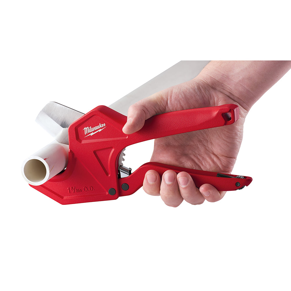 Red Milwaukee ratcheting pipe cutter with replacement blade held in hand, showing cutting wheel and adjustment mechanism.