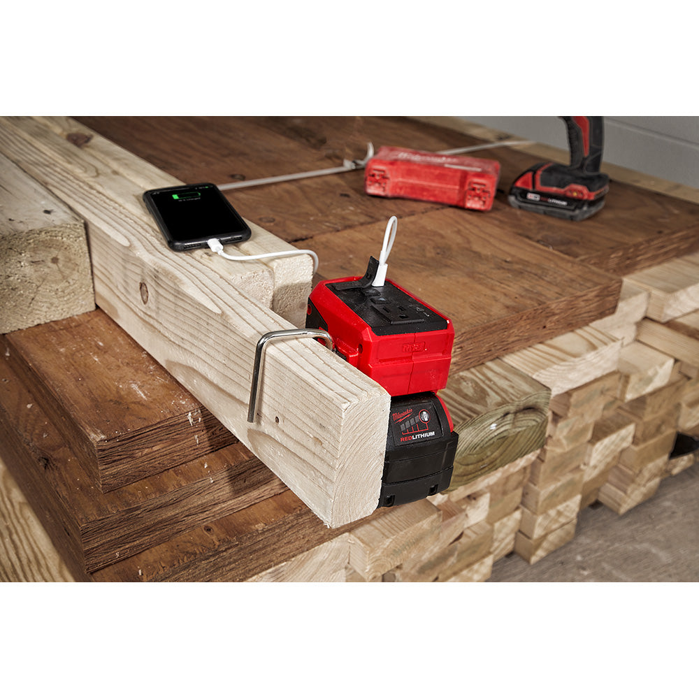 Milwaukee M18 TOP-OFF power supply in red and black mounted on wooden beam, charging smartphone and battery.