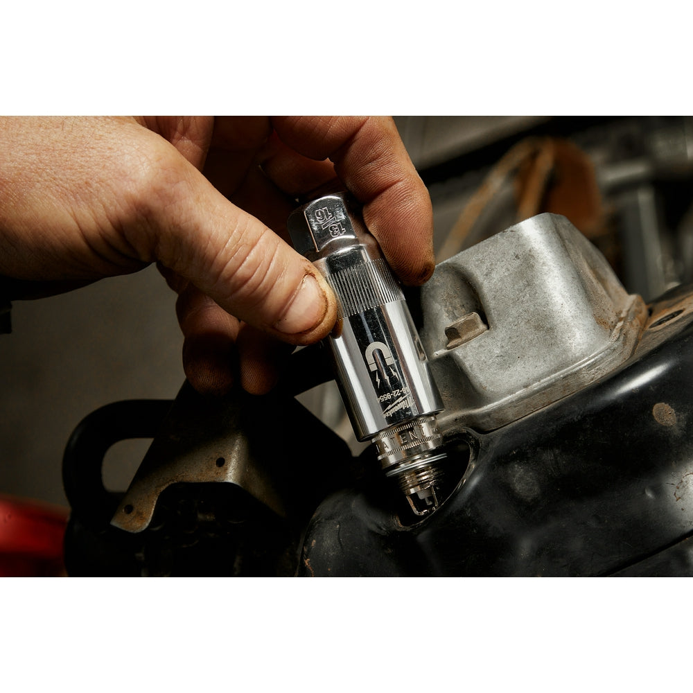 Milwaukee magnetic spark plug socket held in hand positioned over an engine component.