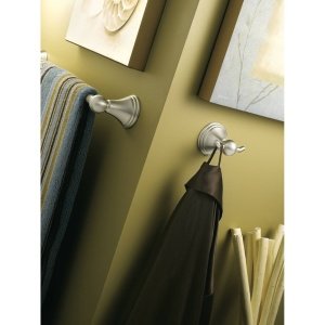 Chrome towel bar mounted on yellow wall holding gray and black towels.