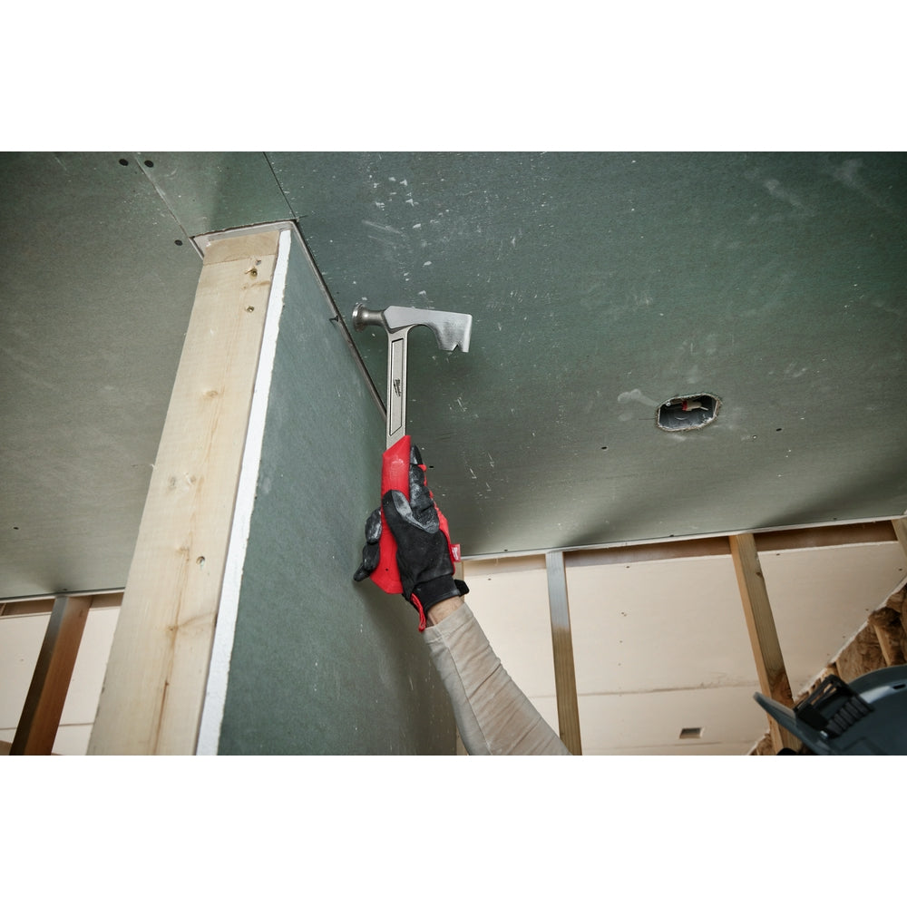 Red and black drywall hammer with curved claw head and gray handle being used on drywall.