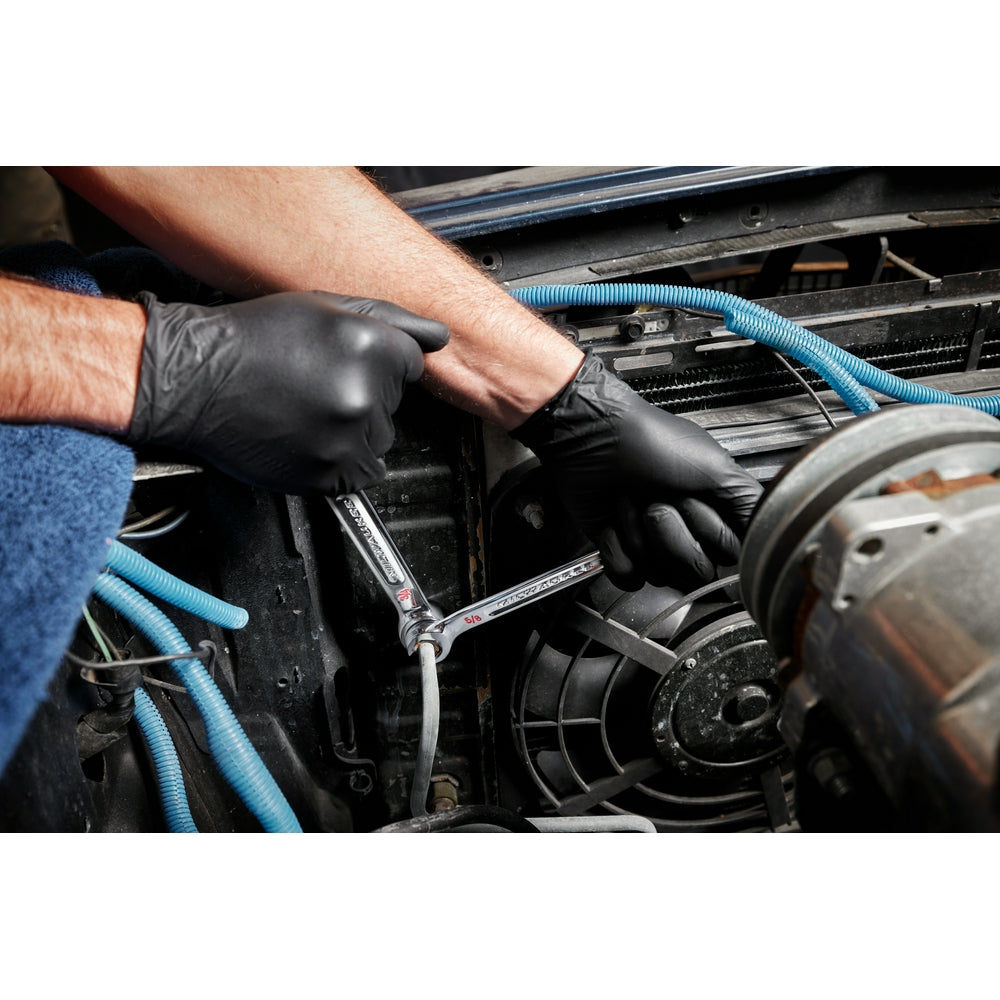 Double end flare nut wrench being used on engine components by a gloved hand.