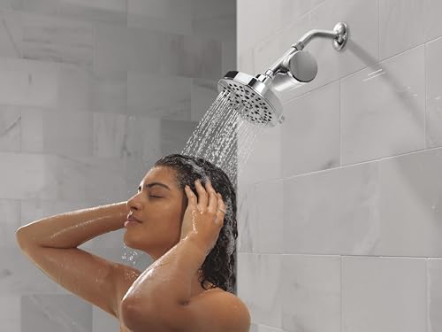 Chrome shower filter head mounted on tile wall with water stream flowing over person's head during shower.