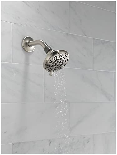 Brushed nickel shower head with curved arm mounted on marble tile wall, water streaming downward from multiple jets.