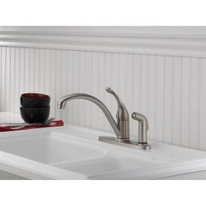Chrome single-handle kitchen faucet with curved spout and side spray attachment mounted on sink countertop.