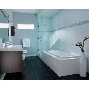 Chrome shower trim with controls mounted on light blue tile wall above white bathtub in bathroom.