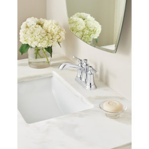 Oil rubbed bronze two-handle centerset faucet installed on white bathroom sink with marble countertop.