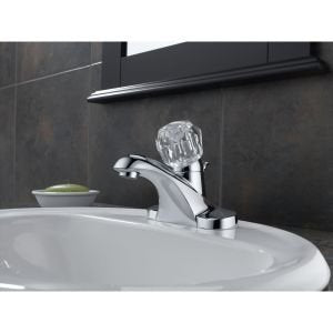 Chrome single-handle centerset faucet with curved spout mounted on white round sink.