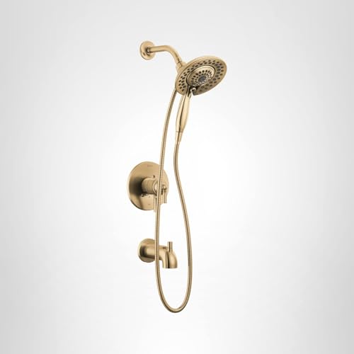 Champagne bronze tub and shower trim with overhead showerhead, hand shower, and adjustable controls mounted on wall.