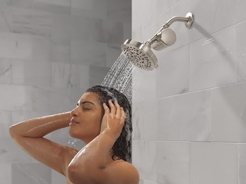 Stainless steel shower filter head with curved arm mounted on white tile wall, dispensing water stream.