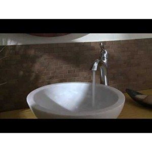 Oil rubbed bronze single-hole bathroom faucet with deck plate installed on white vessel sink.