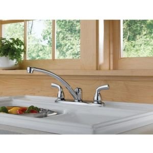 Chrome two-handle kitchen faucet with curved spout installed on white sink counter.
