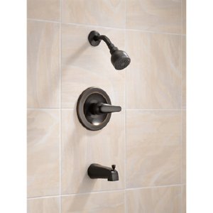 Oil rubbed bronze tub and shower trim with lever handle, spout, and showerhead mounted on tiled wall.
