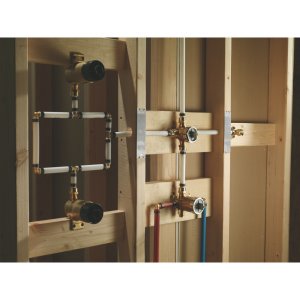 Delta R11000 brass diverter valve with multiple outlet ports and adjustment settings mounted in wall framing.