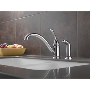 Chrome single-handle kitchen faucet with curved spout and matching spray attachment on countertop.
