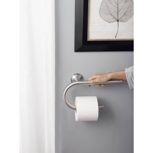 Chrome grab bar with integrated toilet paper holder mounted on gray wall.
