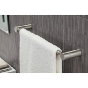 Brushed nickel towel bar mounted on gray tile wall with white towel draped over it.