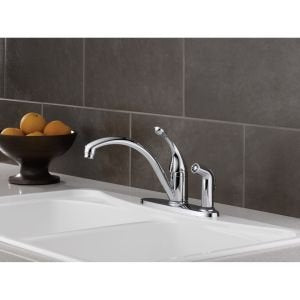 Chrome single-handle kitchen faucet with curved spout and integrated side spray mounted on white sink.