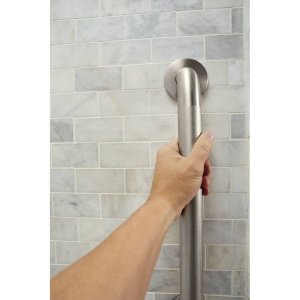 Stainless steel grab bar with peened finish mounted on tiled bathroom wall, hand gripping it for support.