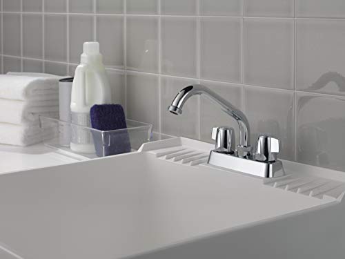 Chrome two-handle laundry faucet with curved spout mounted on white sink, white subway tile backsplash visible.