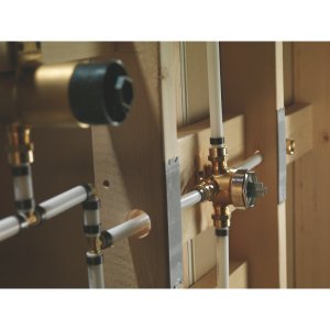 Delta brass diverter valve with black handle mounted on white PVC pipe frame.